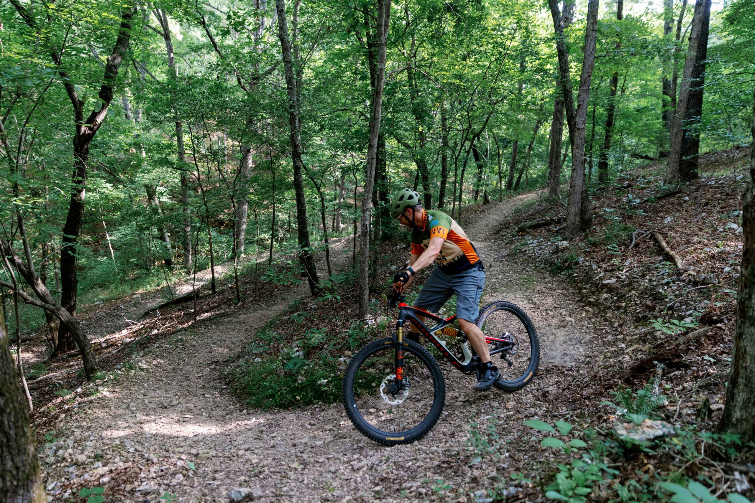 Mountain biker rounding a curve on forested singletrack at Welling Ridge Trails