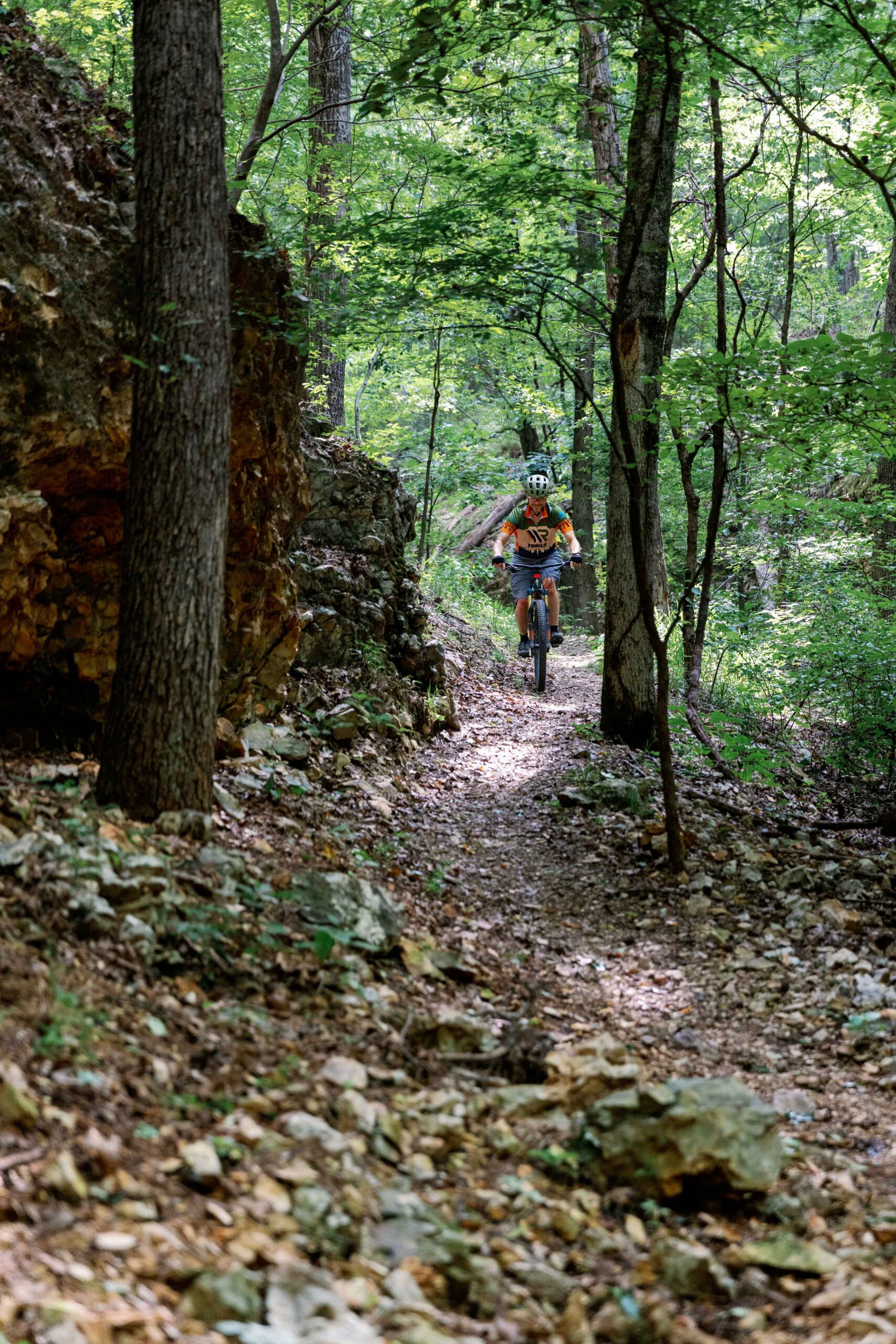 Mountain biker riding singletrack past a rock bluff at Welling Ridge Trails
